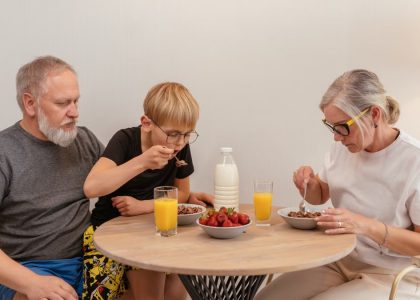 A family of three enjoying breakfast around a wooden table at home.