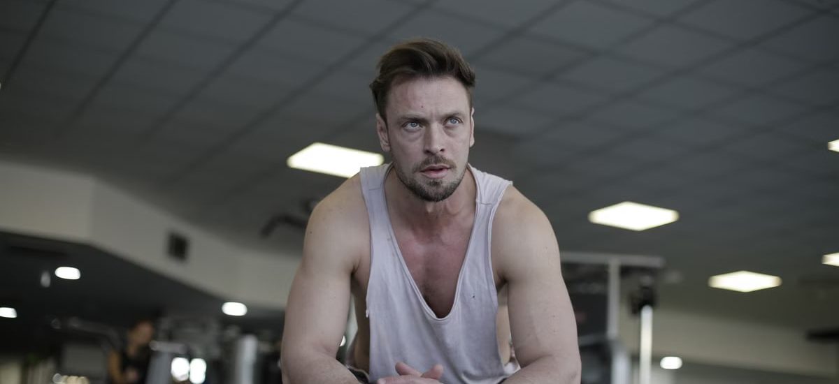 A man pauses to rest after a demanding exercise session at the gym, showcasing fitness and determination.