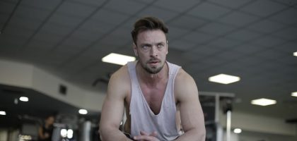 A man pauses to rest after a demanding exercise session at the gym, showcasing fitness and determination.